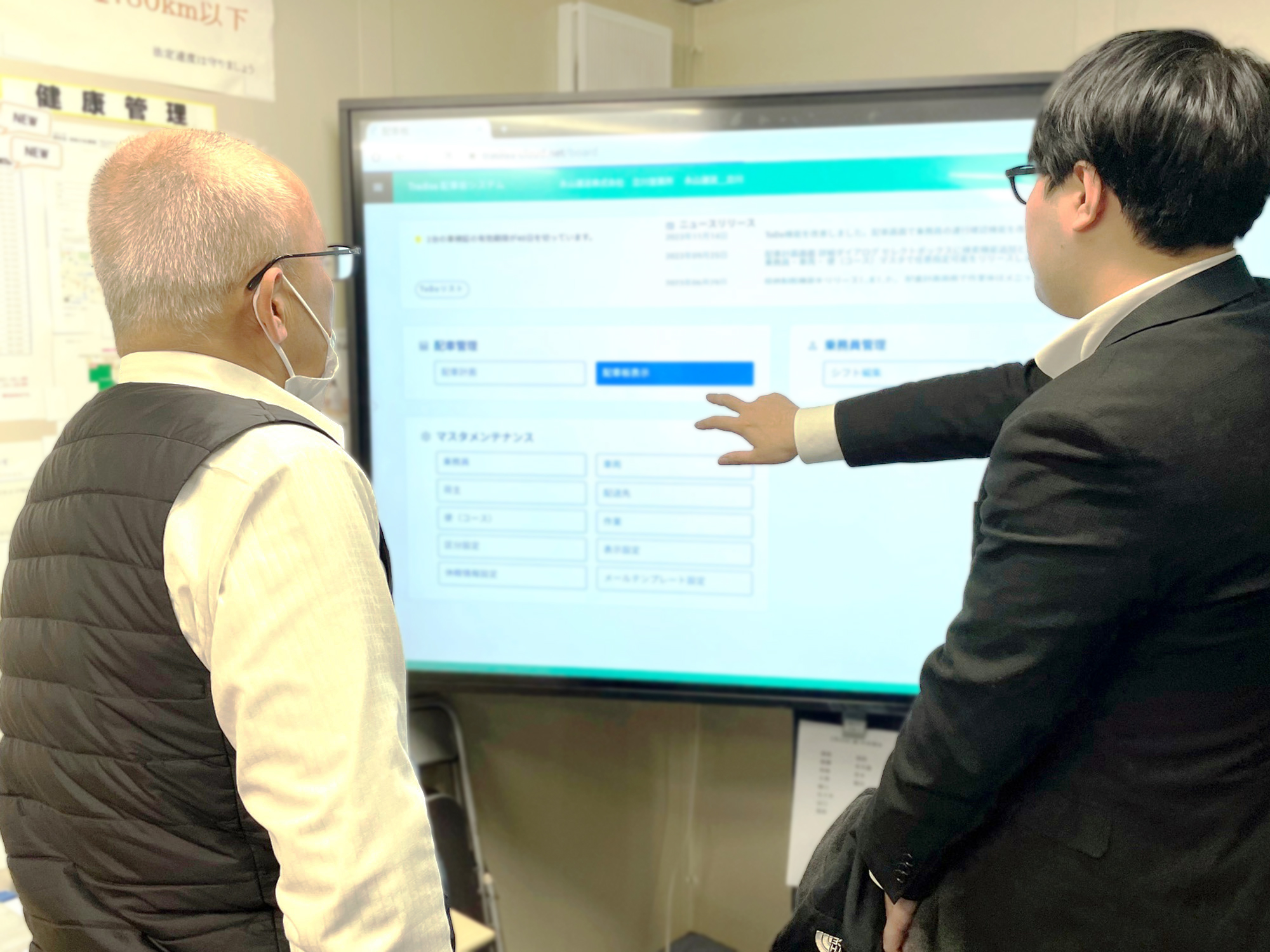 Tradissの75インチタッチパネルを前に 動作を確認しながら話し合う黒澤様と日本情報システム 濱尾